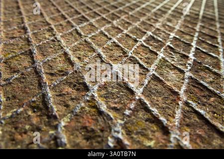 Close-up of a rusted metal plate with embossed rhombic geometric patterns, highlighting corrosion, texture, and industrial design. Ideal for backgrou Stock Photo