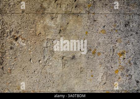 Close-up of a cement wall with rust spots, small cracks, and holes, showcasing texture and weathered details Stock Photo