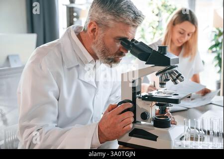 Focused on work. Two doctors are indoors together. Senior man with young woman. Stock Photo