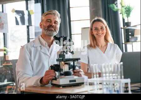 Focused on work. Two doctors are indoors together. Senior man with young woman. Stock Photo