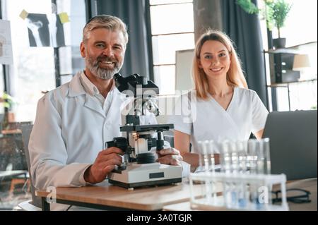 Focused on work. Two doctors are indoors together. Senior man with young woman. Stock Photo