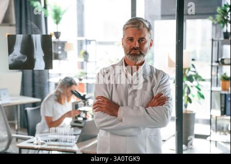 Man is standing in front of woman. Two clinic workers are indoors together. Stock Photo