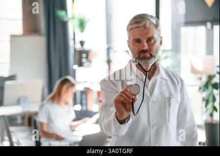 Man is standing in front of woman. Two clinic workers are indoors together. Stock Photo