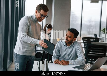 Guys are talking with each other. Men and woman are working in the office together. Stock Photo