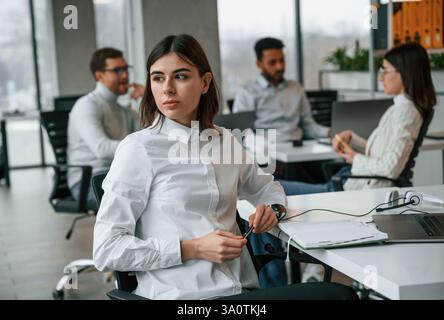 Woman is working by laptop. Four people are working in the office together. Stock Photo