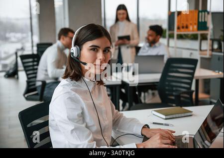 Woman is working by laptop. Four people are working in the office together. Stock Photo