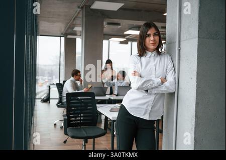 Gorgeous woman is in the front of her colleagues. Four people are working in the office together. Stock Photo
