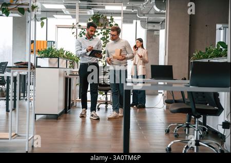 Holding eco boxes and tablet. Men and woman are working in the office together. Stock Photo