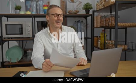 Mature caucasian man smiling in modern office setting wearing white shirt and glasses surrounded by shelves with organized items and papers on wooden Stock Photo