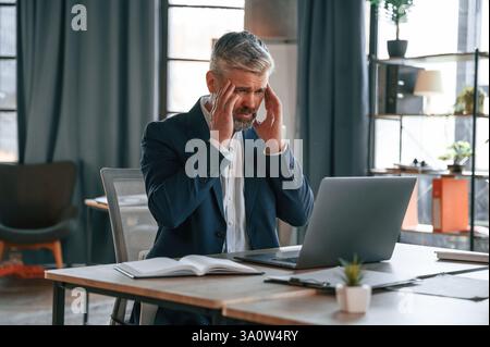 Feeling bad, tired, having headache, stressful. Senior businessman is working in the office. Stock Photo