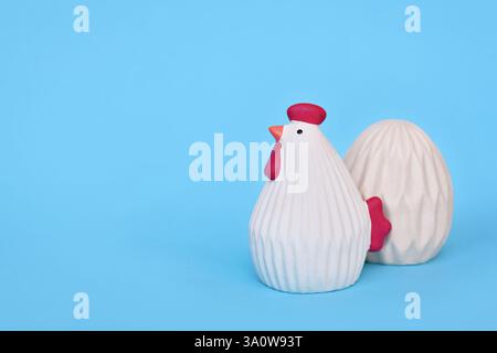 Ceramic Easter chicken and egg decoration objects on blue background with copy space Stock Photo