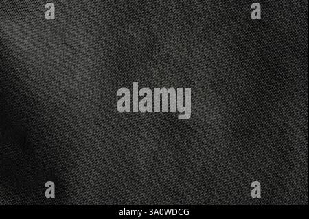 Close-up view of textured black fabric showcasing intricate patterns and depth in soft lighting. Stock Photo