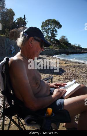 Tourist Reading Book on Vouliagmeni  Beach Attica Greece Stock Photo