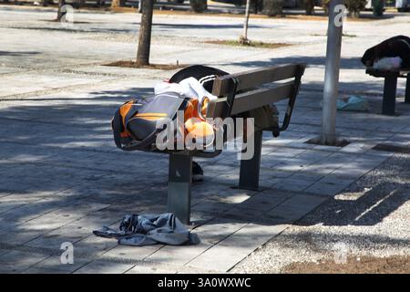 Homeless man Sleeping on Park Bench during the Day Glyfada Athens Greece Stock Photo