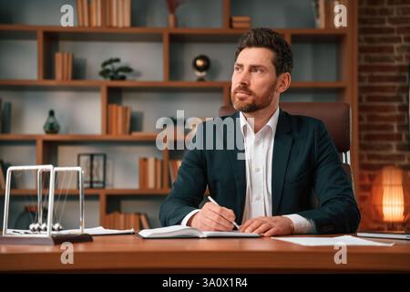 Writing down the ideas. Businessman in formal clothes is working indoors. Stock Photo