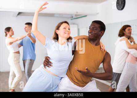 Woman and man practicing modern dance moves in pair during group class Stock Photo