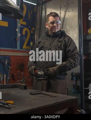 Portrait of male welder working with grinder to grind metal in a workshop. Stock Photo