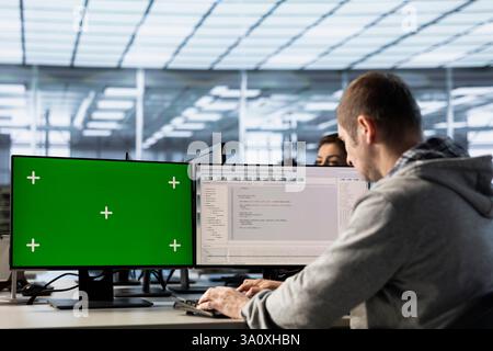 Engineer in server farm using green screen PC to repair equipment storing datasets. IT professional using mockup computer to do debugging on rigs doing computational operations Stock Photo