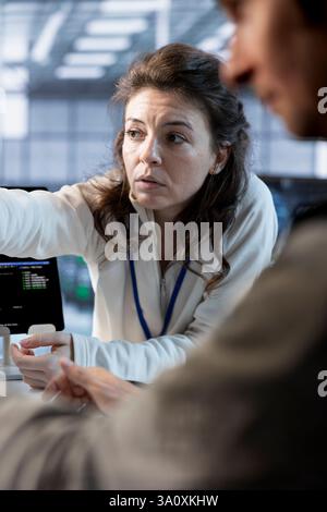 Teamworking colleagues in data center coordinating deployment of server architecture, improving data processing speed. Coworkers doing brainstorming in server farm configuring and testing equipment Stock Photo