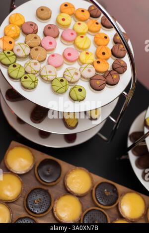 Assorted macarons and tarts displayed on tiered stands Stock Photo