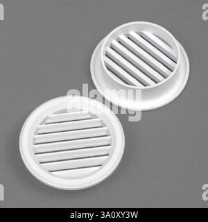 White ventilation grate on a gray background. Round shape. An element of the ventilation system. Stock Photo