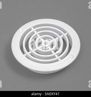 White ventilation grate on a gray background. Round shape. An element of the ventilation system. Stock Photo