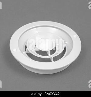 White ventilation grate on a gray background. Round shape. An element of the ventilation system. Stock Photo