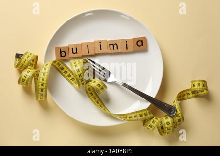 Plate with word Bulimia, fork and measuring tape on beige background, top view Stock Photo
