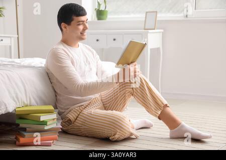 Young man reading book in bedroom Stock Photo