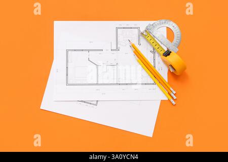 Architect's supplies with house plans on orange background Stock Photo