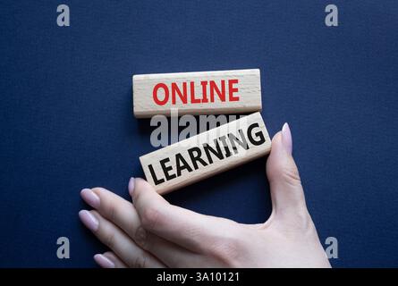 Online learning symbol. Wooden blocks with words Online learning. Beautiful deep blue background. Businessman hand. Business and Online learning conce Stock Photo
