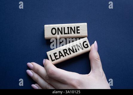 Online learning symbol. Wooden blocks with words Online learning. Beautiful deep blue background. Businessman hand. Business and Online learning conce Stock Photo