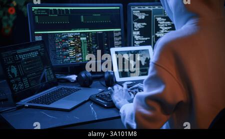 Blue neon light. Young professional female hacker is indoors by computer with lot of information on displays. Stock Photo