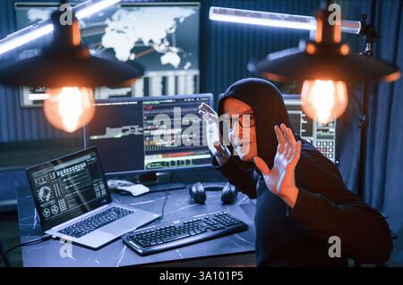 Got caught. With hands up. Male professional hacker is sitting by computer, conception of virus. Stock Photo