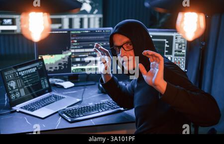 Got caught. With hands up. Male professional hacker is sitting by computer, conception of virus. Stock Photo