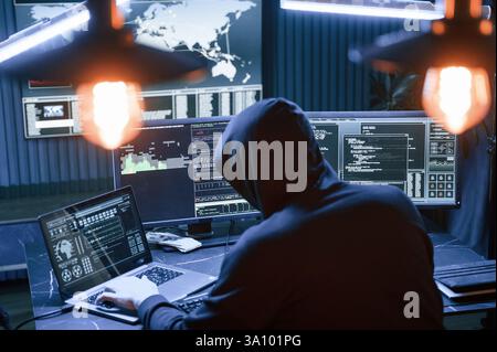 Rear view. Male professional hacker is sitting by computer, conception of virus. Stock Photo