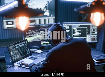 Rear view. Male professional hacker is sitting by computer, conception of virus. Stock Photo