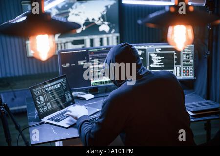 Rear view. Male professional hacker is sitting by computer, conception of virus. Stock Photo