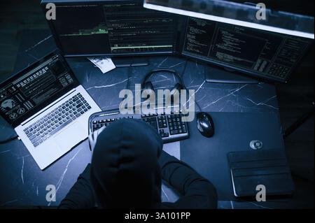 Male professional hacker is sitting by computer, conception of virus. Stock Photo