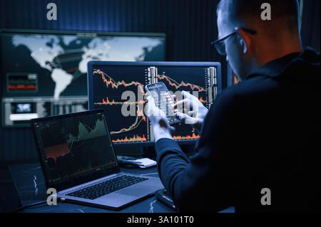 Financial Analyst Working on a Computer with Multi-Monitor Workstation with Real-Time Stocks, Commodities and Exchange Market Charts Stock Photo