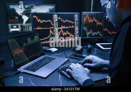 Financial Analyst Working on a Computer with Multi-Monitor Workstation with Real-Time Stocks, Commodities and Exchange Market Charts Stock Photo