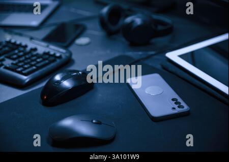 Close up view of table with smartphone, pc mouse, keyboard and headphones. Stock Photo