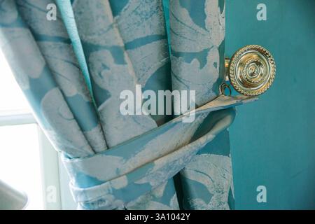 Close up of a blue curtain with a brass knob on it. Stock Photo