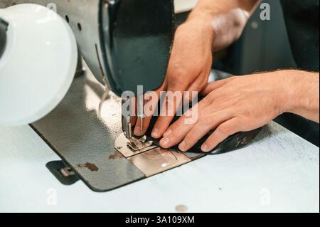 Sewing process. Close up view. Man's hands on the table, using stationary machine. Stock Photo
