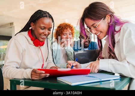 Excited diverse students engaged in collaborative learning while studying together and sharing ideas on homework assignments in a dynamic group setting during their university campus. High quality photo Stock Photo