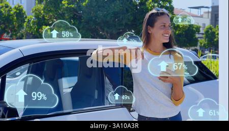 Image of cloud icons over caucasian woman using smartphone Stock Photo