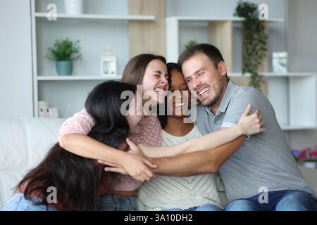 Four happy friends or roommates hugging sitting on a couch at home Stock Photo