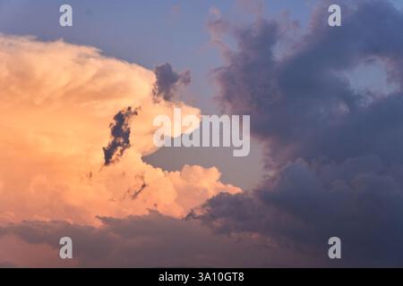 Detailed view of towering cumulus clouds illuminated by the orange glow of sunset over the Costa degli Aranci in Soverato, Calabria, Italy. Stock Photo