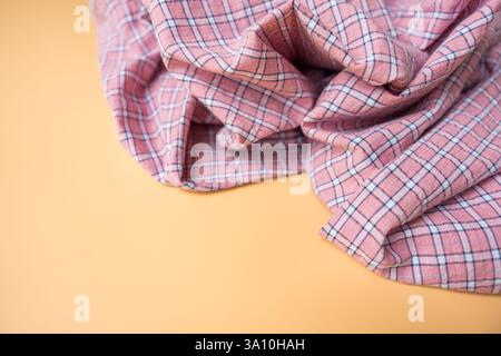 Pink plaid fabric with soft folds on beige background, textile material close-up. Stock Photo