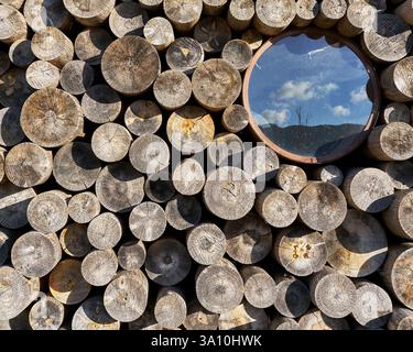 Round glass window embedded in the wood stack facade of La Catasta reflecting the sky, Campotenese, Pollino National Park, Calabria, Italy. Stock Photo